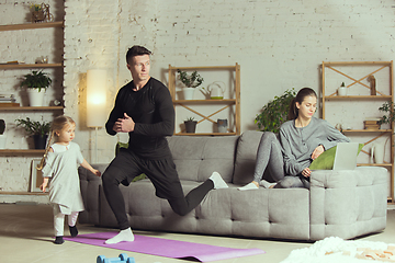 Image showing Young man exercising fitness, aerobic, yoga at home, sporty lifestyle. Getting active during lockdown, quarantine. Home gym.