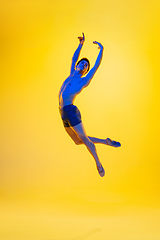 Image showing Young and graceful ballet dancer isolated on yellow studio background in neon light. Art, motion, action, flexibility, inspiration concept.