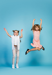 Image showing Happy kids, girls isolated on blue studio background. Look happy, cheerful, sincere. Copyspace. Childhood, education, emotions concept