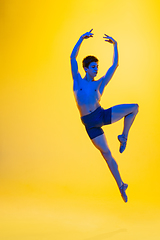 Image showing Young and graceful ballet dancer isolated on yellow studio background in neon light. Art, motion, action, flexibility, inspiration concept.