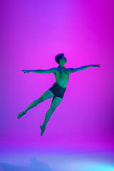 Image showing Young and graceful ballet dancer isolated on purple studio background in neon light. Art, motion, action, flexibility, inspiration concept.