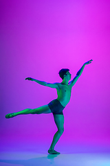 Image showing Young and graceful ballet dancer isolated on purple studio background in neon light. Art, motion, action, flexibility, inspiration concept.