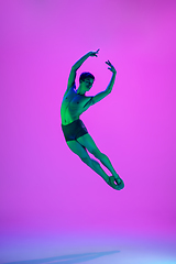 Image showing Young and graceful ballet dancer isolated on purple studio background in neon light. Art, motion, action, flexibility, inspiration concept.