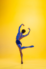 Image showing Young and graceful ballet dancer isolated on yellow studio background in neon light. Art, motion, action, flexibility, inspiration concept.