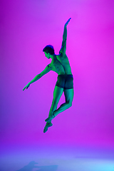 Image showing Young and graceful ballet dancer isolated on purple studio background in neon light. Art, motion, action, flexibility, inspiration concept.