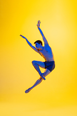 Image showing Young and graceful ballet dancer isolated on yellow studio background in neon light. Art, motion, action, flexibility, inspiration concept.