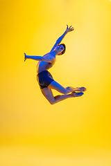 Image showing Young and graceful ballet dancer isolated on yellow studio background in neon light. Art, motion, action, flexibility, inspiration concept.