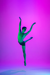 Image showing Young and graceful ballet dancer isolated on purple studio background in neon light. Art, motion, action, flexibility, inspiration concept.