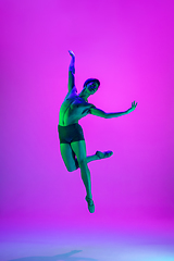 Image showing Young and graceful ballet dancer isolated on purple studio background in neon light. Art, motion, action, flexibility, inspiration concept.