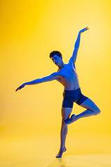 Image showing Young and graceful ballet dancer isolated on yellow studio background in neon light. Art, motion, action, flexibility, inspiration concept.