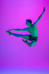 Image showing Young and graceful ballet dancer isolated on purple studio background in neon light. Art, motion, action, flexibility, inspiration concept.