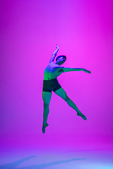 Image showing Young and graceful ballet dancer isolated on purple studio background in neon light. Art, motion, action, flexibility, inspiration concept.