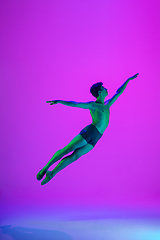 Image showing Young and graceful ballet dancer isolated on purple studio background in neon light. Art, motion, action, flexibility, inspiration concept.