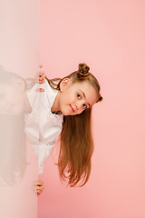 Image showing Happy kid, girl isolated on coral pink studio background. Looks happy, cheerful, sincere. Copyspace. Childhood, education, emotions concept