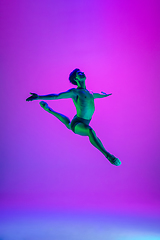 Image showing Young and graceful ballet dancer isolated on purple studio background in neon light. Art, motion, action, flexibility, inspiration concept.