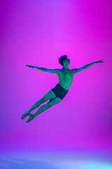 Image showing Young and graceful ballet dancer isolated on purple studio background in neon light. Art, motion, action, flexibility, inspiration concept.