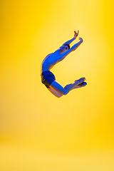 Image showing Young and graceful ballet dancer isolated on yellow studio background in neon light. Art, motion, action, flexibility, inspiration concept.