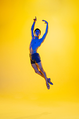 Image showing Young and graceful ballet dancer isolated on yellow studio background in neon light. Art, motion, action, flexibility, inspiration concept.