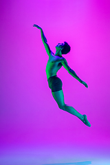 Image showing Young and graceful ballet dancer isolated on purple studio background in neon light. Art, motion, action, flexibility, inspiration concept.