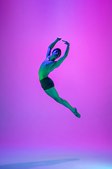 Image showing Young and graceful ballet dancer isolated on purple studio background in neon light. Art, motion, action, flexibility, inspiration concept.