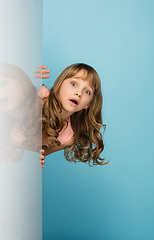 Image showing Happy kid, girl isolated on blue studio background. Looks happy, cheerful, sincere. Copyspace. Childhood, education, emotions concept