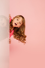 Image showing Happy kid, girl isolated on coral pink studio background. Looks happy, cheerful, sincere. Copyspace. Childhood, education, emotions concept