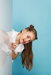 Image showing Happy kid, girl isolated on blue studio background. Looks happy, cheerful, sincere. Copyspace. Childhood, education, emotions concept