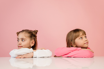 Image showing Happy kids, girls isolated on coral pink studio background. Look happy, cheerful, sincere. Copyspace. Childhood, education, emotions concept