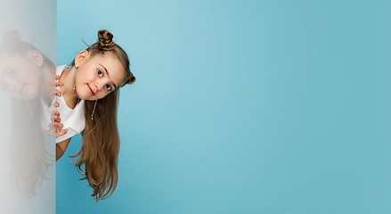 Image showing Happy kid, girl isolated on blue studio background. Looks happy, cheerful, sincere. Copyspace. Childhood, education, emotions concept