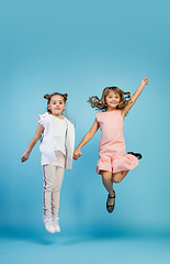 Image showing Happy kids, girls isolated on blue studio background. Look happy, cheerful, sincere. Copyspace. Childhood, education, emotions concept