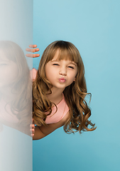 Image showing Happy kid, girl isolated on blue studio background. Looks happy, cheerful, sincere. Copyspace. Childhood, education, emotions concept