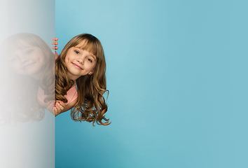 Image showing Happy kid, girl isolated on blue studio background. Looks happy, cheerful, sincere. Copyspace. Childhood, education, emotions concept