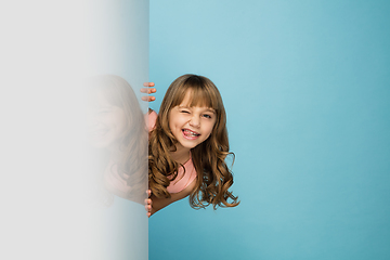 Image showing Happy kid, girl isolated on blue studio background. Looks happy, cheerful, sincere. Copyspace. Childhood, education, emotions concept