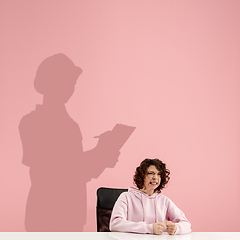 Image showing Young woman dreaming about future in big science during her work in office. Becoming a legend. Shadow of dreams on the wall behind her. Copyspace.