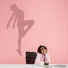 Image showing Young woman dreaming about future in big sport during her work in office. Becoming a legend. Shadow of dreams on the wall behind her. Copyspace.