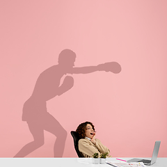 Image showing Young woman dreaming about future in big sport during her work in office. Becoming a legend. Shadow of dreams on the wall behind her. Copyspace.