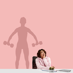 Image showing Young woman dreaming about future in big sport during her work in office. Becoming a legend. Shadow of dreams on the wall behind her. Copyspace.