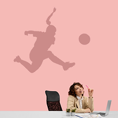Image showing Young woman dreaming about future in big sport during her work in office. Becoming a legend. Shadow of dreams on the wall behind her. Copyspace.