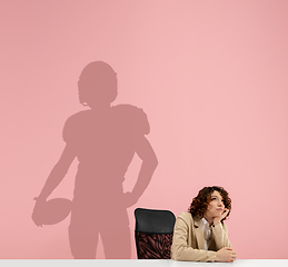 Image showing Young woman dreaming about future in big sport during her work in office. Becoming a legend. Shadow of dreams on the wall behind her. Copyspace.