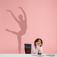 Image showing Young woman dreaming about future in big sport during her work in office. Becoming a legend. Shadow of dreams on the wall behind her. Copyspace.