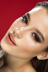 Image showing Portrait of female fashion model isolated on red studio background. Style and beauty concept. Close up.