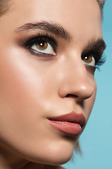 Image showing Close up of female fashion model\'s face isolated on blue studio background. Style and beauty concept.