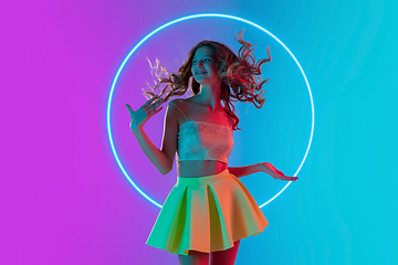 Image showing Beautiful girl in fashionable, romantic outfit on gradient background in neon light with glowing neoned blue circle