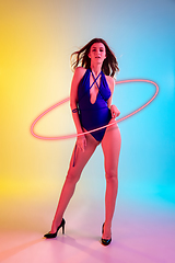 Image showing Fashion portrait of young fit and sportive caucasian woman in stylish swimwear on gradient background with pink neoned circle