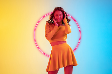 Image showing Beautiful girl in fashionable, romantic outfit on gradient background in neon light with glowing neoned pink circle