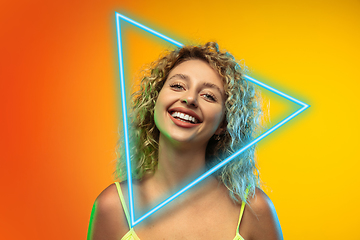 Image showing Caucasian woman\'s portrait isolated on gradient studio background in neon light with glowing triangle. Concept of human emotions, facial expression, sales, ad.