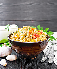 Image showing Barley porridge with minced meat in bowl on black wooden board