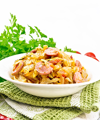 Image showing Cabbage stew with sausages in white plate on wooden board