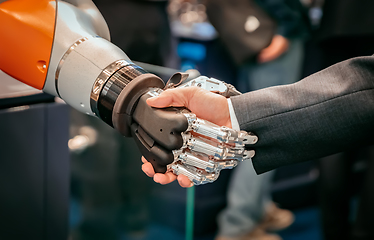 Image showing Hand of a businessman shaking hands with a Android robot.