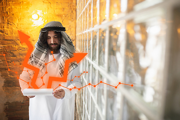 Image showing Arabian businessman working in office, business centre using device, gadget. Modern saudi lifestyle. Ethnicity, finance, income increase